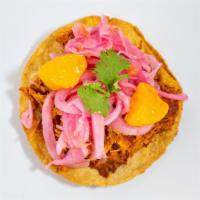 Panucho · Small handmade tostada stuffed with beans, topped with cochinita pibil, red onions with haba...