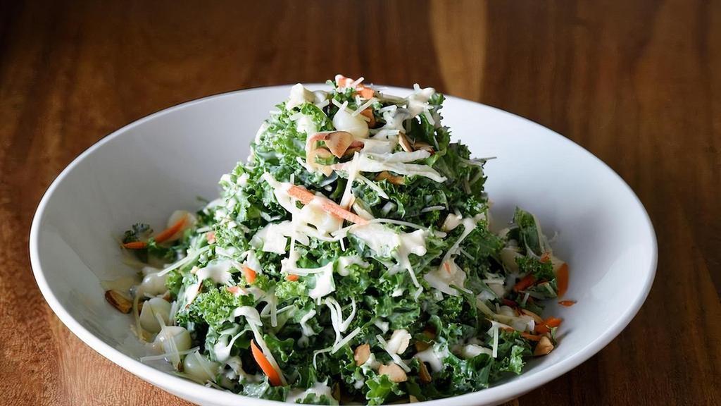 Kale salad · Curly green kale, mixed cabbage, carrots, cherry tomatoes, choclo, golden raisins, toasted almonds, parmesan cheese, & Rocoto miso dressing.