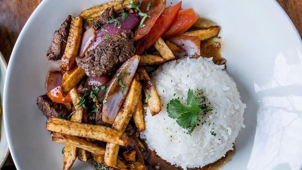 Lomo saltado · Traditional Peruvian favorite! Wok stir-fried beef tenderloin with onions, tomatoes in ginger-infused soy sauce, french fries & served with jasmine rice.. *Contains gluten, shellfish (oyster sauce) & soy