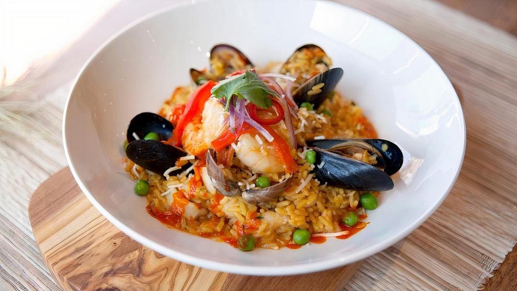 Arroz con mariscos · Aromatic saffron rice cooked in Ají Amarillo & Ají Panca fish fumé. Comes with fresh mussels, clams, shrimp, calamari, fish, parmesan cheese & salsa criolla. Drizzled with Rocoto acevichado sauce.. Contains: dairy & shellfish.