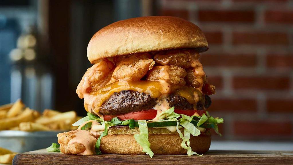 Volcano Burger · Beef burger, crispy shrimp, creamy Cajun sauce, Cheddar cheese, house-made pickles, aioli, lettuce, tomato. Served with perfectly seasoned crispy fries.