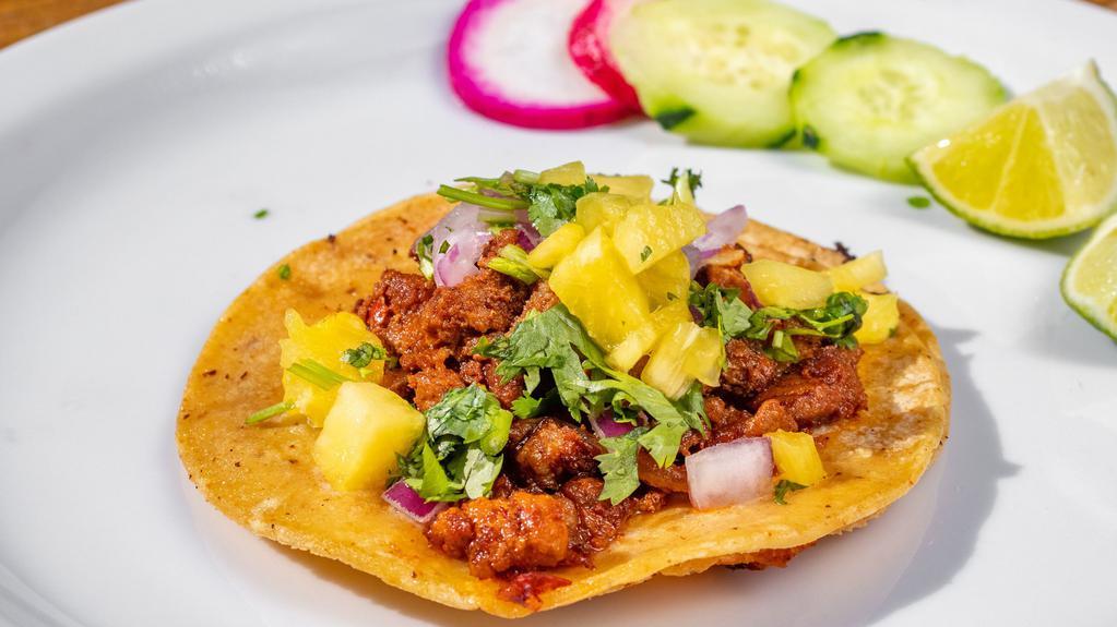 Al Pastor Taco · Corn tortilla, marinated pork, cilantro, onions, and pineapple. Complimentary garnish: radish, cucumber, lime, and salsa.