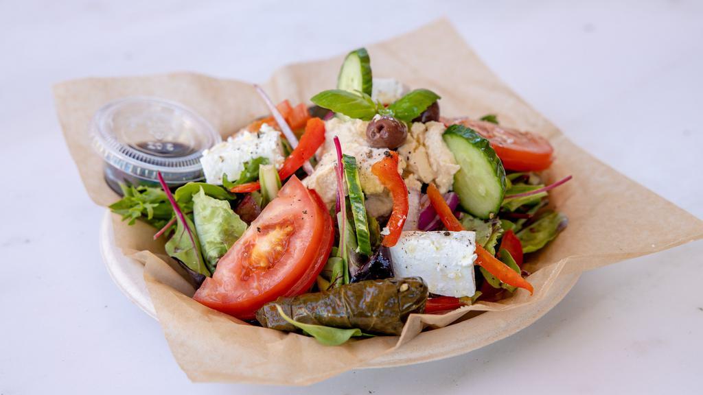 Greek Salad · Hummus, dolmas, red onions, mixed greens, cucumber, artichoke hearts, garbanzo beans, feta cheese, olives, roasted red peppers, basil, olive oil, and vinegar.