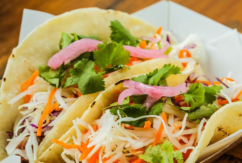 Banh Mi Taco · Corn tortilla topped with Xa-Xiu pork, shredded cabbage mix, pickled carrots-daikon, pickled red onion, cilantro and drizzled with our lime mayo-cha sauce.