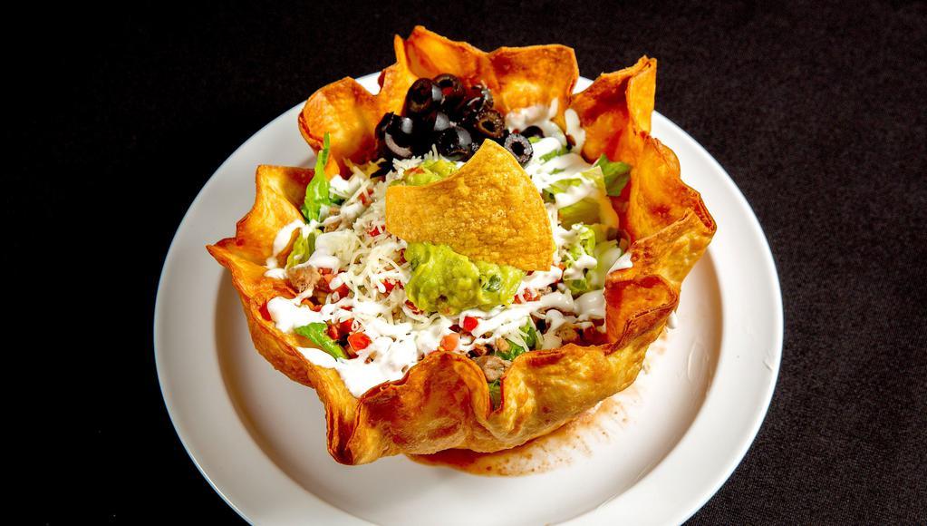 Fish Taco Salad · Large crispy flour tortilla layered with refried beans and topped with romaine lettuce, cheese, olives, pico de gallo, sour cream, guacamole, and your choice of fish.