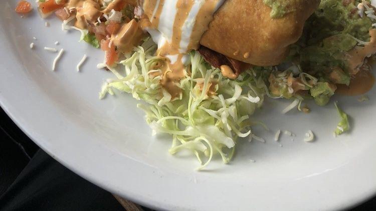Fish Chimichanga · Golden-fried flour tortilla stuffed with rice, cheese, orange sauce, grilled peppers and onions, and your choice of fish. Topped with guacamole, sour cream, and pico de gallo.