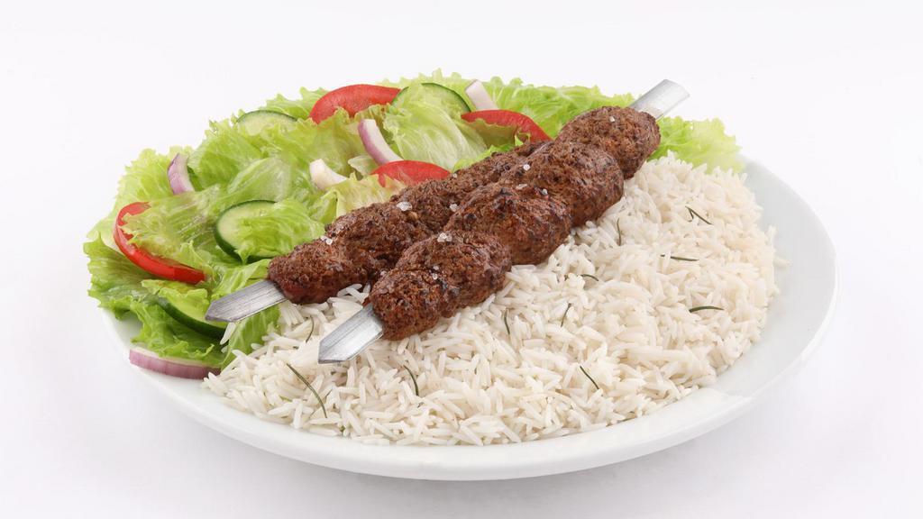 The Adana Kabob Plate · Adana style kabob sizzling over bed of rice, with side of salad, hummus and pita bread.