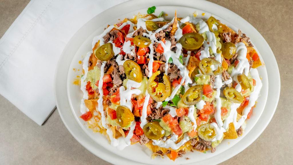 Nachos · Crispy tortilla chips layered with beans, jack cheese and choice of steak, chicken, shredded or marinated pork. Topped with guacamole, sour cream, diced tomato, jalapeño, sprinkled with onions and cilantro.