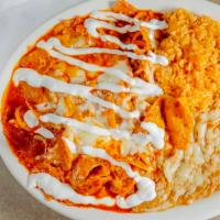 Chilaquiles · Tortilla strips mixed with eggs and onions in a red home style sauce. Topped with melted che...