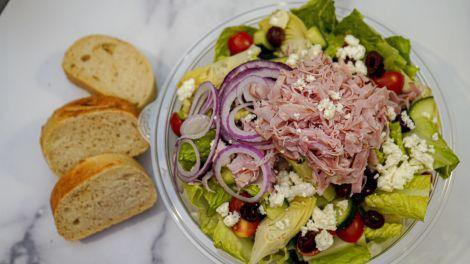Greek Salad · Chopped romaine, ham, cucumbers, tomatoes, artichoke hearts, kalamata olives, red onions, feta cheese, greek dressing, served with sourdough bread.