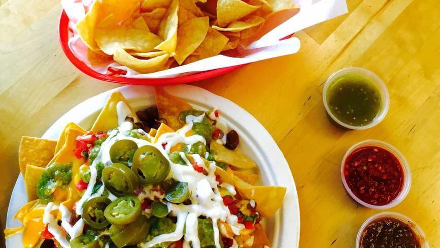 Regular Nachos · A bed of fresh chips covered with cheddar cheese sauce and jalapeños.