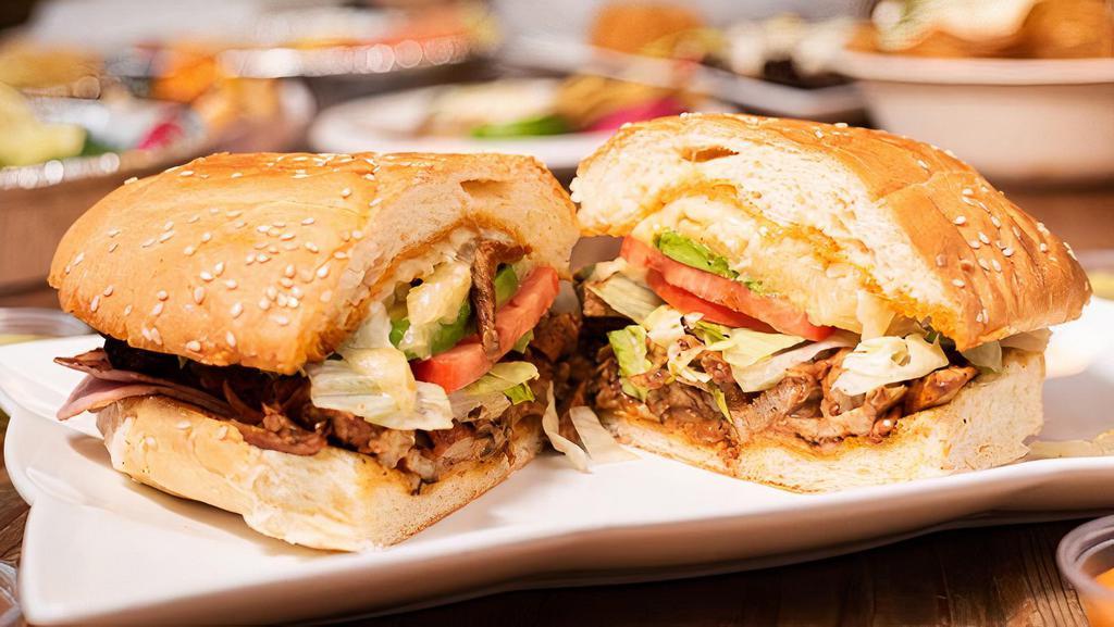 Torta El Bombon · Refried beans, Asada and Chorizo meat with pineapple, grilled onions, mushrooms, bell peppers, lettuce, tomato, avocado, jalapeno, chipotle mayo, and cheese.