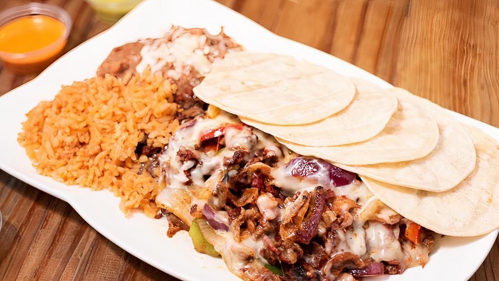Alambre · Carne asada, al pastor, chorizo and bacon, mixed with onions, bell peppers, and melted cheese on top. Rice, beans and corn tortillas on the side.
