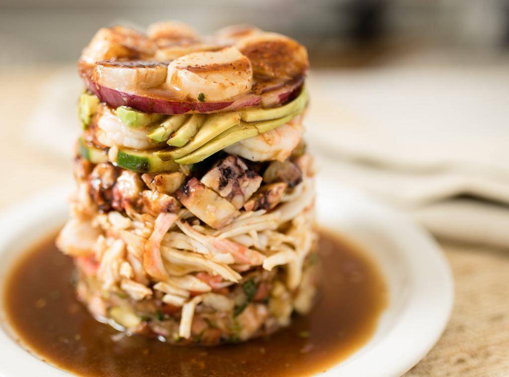 Torre El Tamarindo · Seafood tower, layered: fish ceviche, imitation crab, octopus, cucumber, shrimp, avocado, red onion, scallops, house sauce, and chili powder.