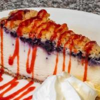 Lemon Blueberry Crumb Cheesecake · A creamy lemon cheesecake topped with blueberries & brown sugar. crumbs sits on a cookie base