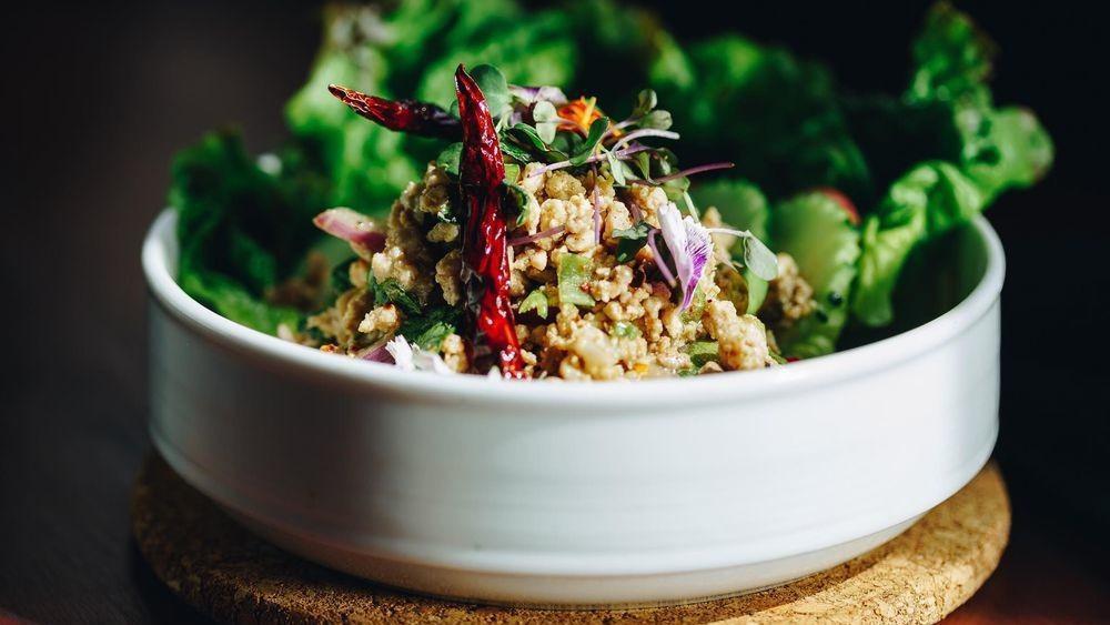 Larb Gai · Spicy. Thai herbal minced chicken salad with spicy lime dressing, toasted rice, roasted chili, red onions, green onions, cilantro, and mint.