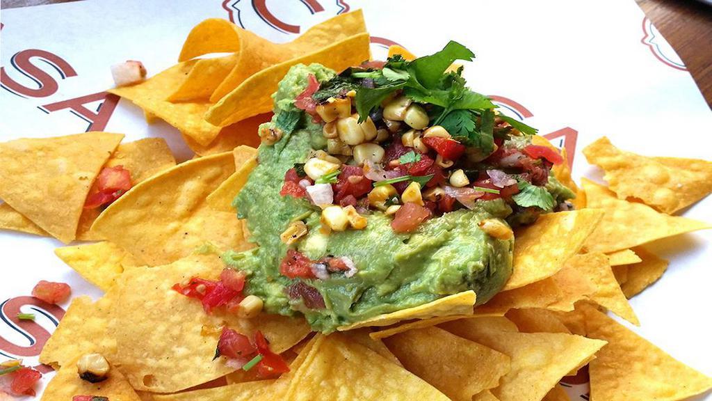 Vegan Housemade Guacamole & Chips · Our signature guacamole made with Roma tomatoes, serrano chile, red onion, garlic, cilantro and lime juice.   Topped with grilled corn salsa, vegan parmesan cheese, cilantro, fleur de sel sea salt and served with our housemade tortilla chips.