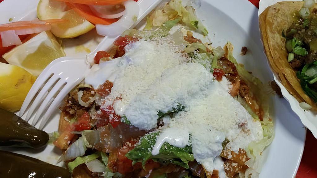  TOSTADA · Toasted corn tortilla topped with refried bean, choice of protein, lettuce, diced tomatoes, sour cream, Mexican powdered cheese, and non-spicy tomato salsa.
