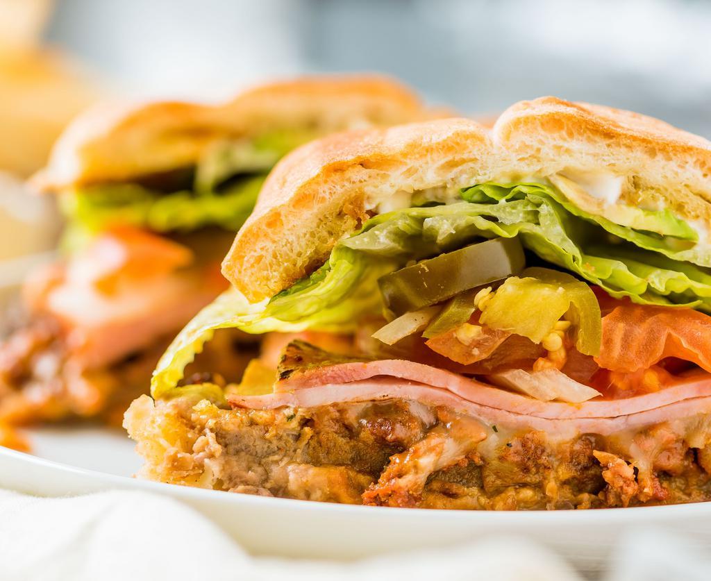 Acapulco · Milanesa, ham, chorizo, refried beans, melted cheese, lettuce, tomato, onion, jalapeños, avocado and mayo on a telera roll. Served with French fries.