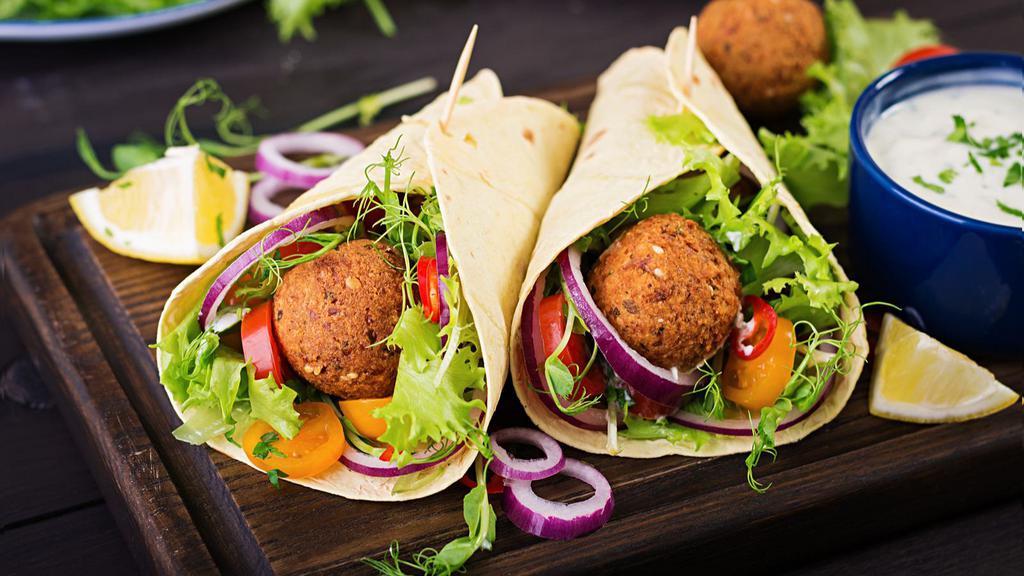 Falafel Deluxe · 2 crispy falafels with lettuce, tomatoes, onions, eggplants, hummus, potatoes, parsley, and tahini sauce all in a lavash bread.