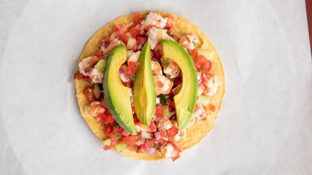 Ceviche Tostada · Fish or shrimp marinated in lime, cilantro, onions, tomato, peppers, cucumber, and avocado.