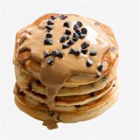 Peanut Butter Chocolate Chip Pancakes · Two large peanut butter and chocolate chips pancakes served with syrup.