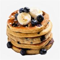 Blueberry Banana Pancakes · Two large blueberry and banana pancakes served with syrup.