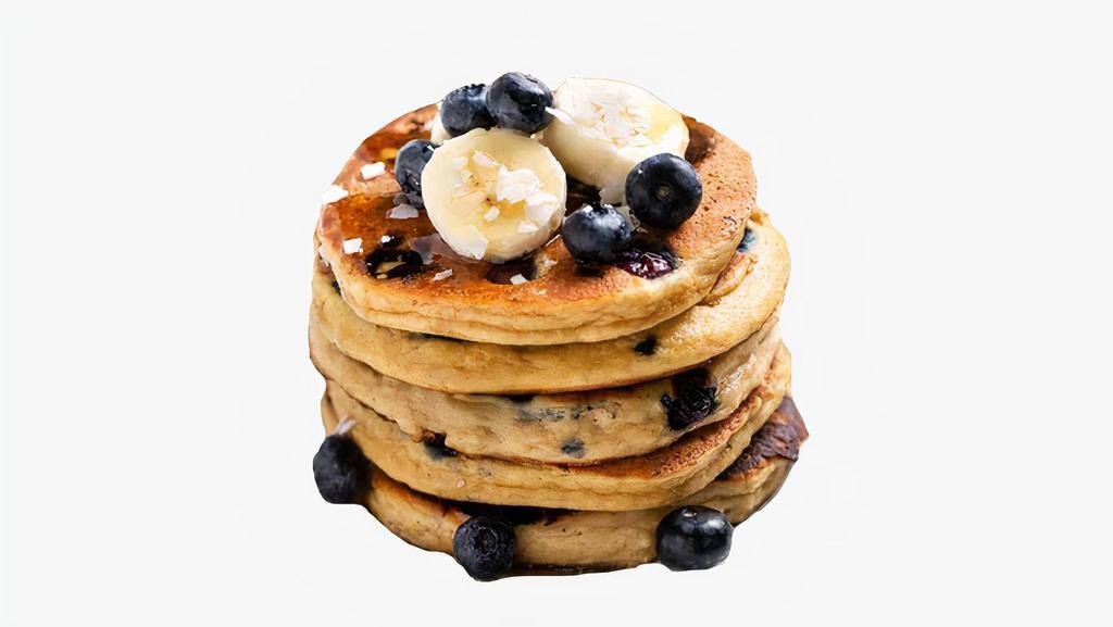 Blueberry Banana Pancakes · Two large blueberry and banana pancakes served with syrup.