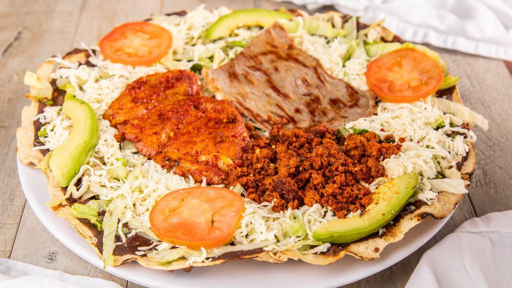 Tlayuda Mixta · A Gigantic thin handcrafted baked corn tortilla imported from oaxaca topped with our black beans puree, lettuce, tomatoes, avocado slices, Mexican cheese, Quesillo, and three meats (Chorizo, Tasajo- Grilled Beef, Cecina enchilada- Marinated pork)