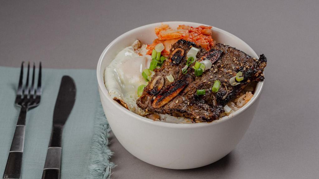 Grilled Chicken Bowl · A bowl filled with grilled chicken over steamed rice, with kimchi, scallions, and fried egg.