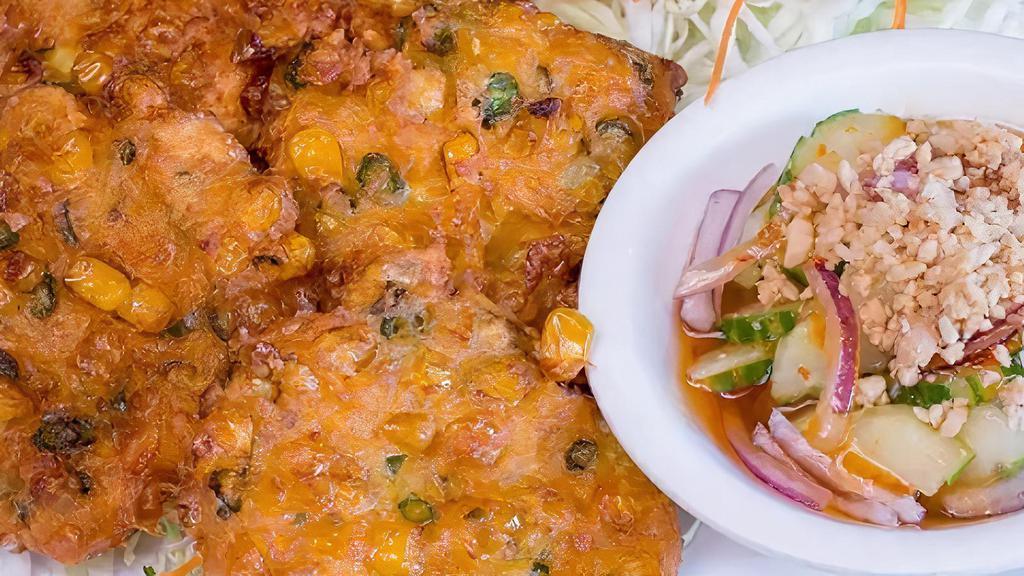 06 - CORN CAKES · Fritters (4) made with corn kernels, chopped green beans, kaffir lime leaves, chili paste, and curry paste. Deep-fried and served with cucumber salad topped with chopped peanuts in a house sweet chili sauce
