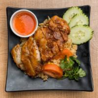 Crispy Fried Chicken Over Fried Rice · Fried chicken cutlet over Thai style fried rice. Topped with cilantro and cucumber. Served w...