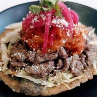 Steak Panucho · Crispy handmade corn tortilla, stuffed with black bean puree, cabbage, pickled onions,  brai...