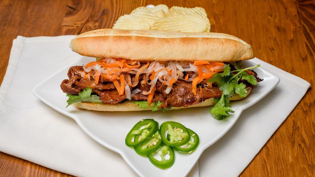 Vietnamese Grilled Pork Bánh Mì · Vietnamese sandwich with slices of grilled pork, pickled vegetables, cilantro, and Vietnamese mayo. served with a side of potato chips.