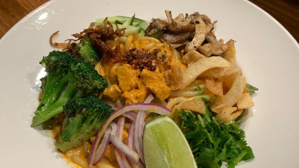 Vegan Tempeh Curry Noodles · Rice noodles in coconut curry sauce, with tempeh, cucumbers, broccoli, mushrooms, cilantro, fried onions, wonton chips, chili oil. Vegan. Medium spicy.
