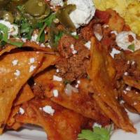 Chilaquiles · Tortilla chips tossed in spicy salsa roja, topped with 2 scrambled eggs, sliced jalapeños, t...