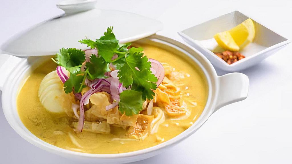 (C) Ohnoh Kawt Swe (Coconut Noodle Soup) · A rich and creamy coconut bisque with flour noodles. Served with chicken, onion, tamarind powder and paprika. Garnished with onion, cilantro and lemon. Serves 10 cups.
