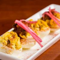 Deviled Eggs · Two classic halves and two halves topped with pulled pork and house-pickled onion.