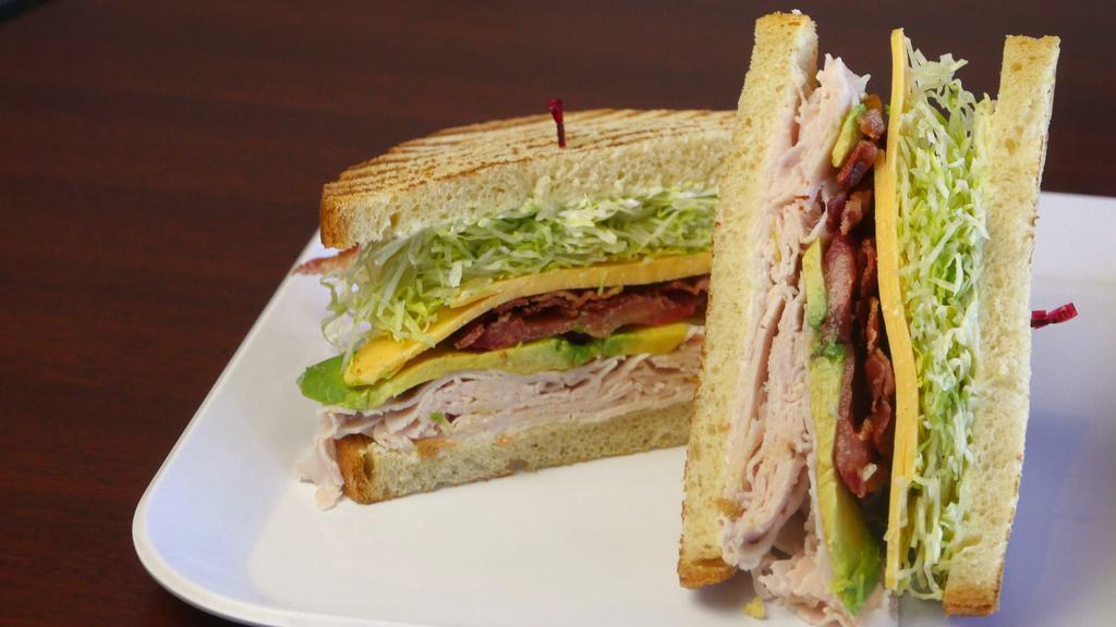 Turkey Club Sandwich · Oven-roasted turkey, bacon, avocado, American cheese on toasted, sliced sourdough with mayonnaise, lettuce, and tomato.