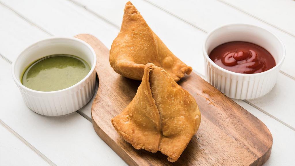 Famous Indian Veg Samosa · Hot fried pastry shells stuffed with roasted cumin potatoes, served with mint and tamarind chutney