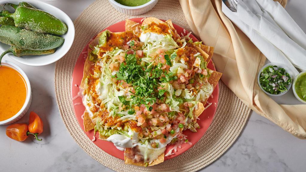 Super Nachos · Chips, beans, cheese, meat, cheese, guacamole, sour cream, lettuce, tomato, and salsa.