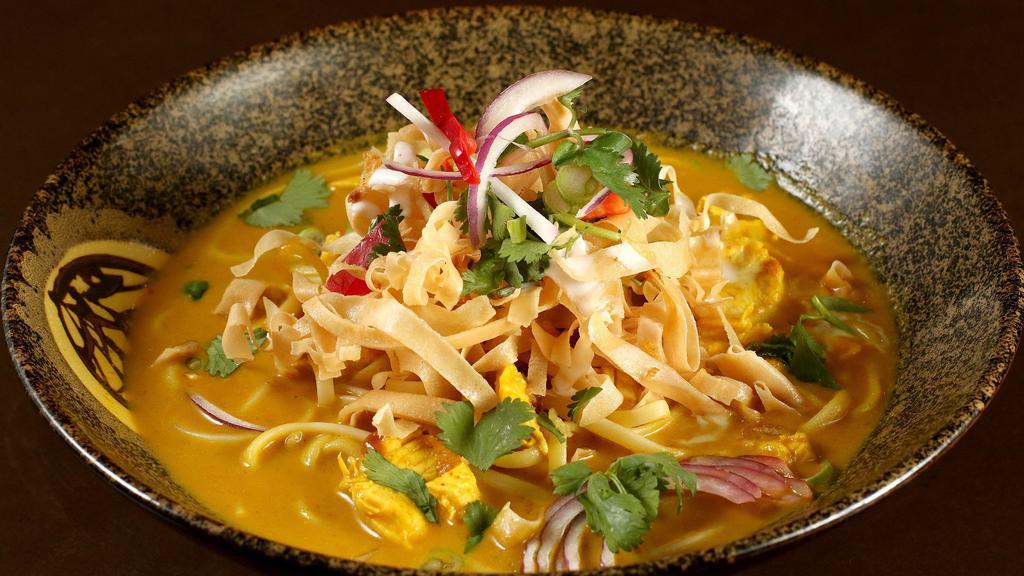 Khao Soi · Northern Thailand dish. Noodles in coconut curry sauce topped with crispy noodle, shallots, cilantro and fresh lemon.