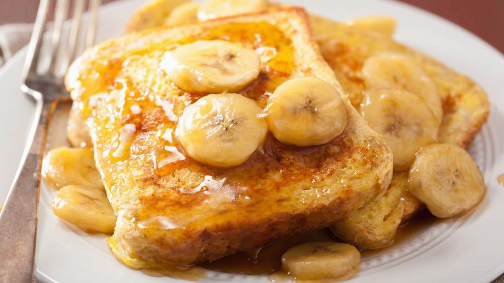 Banana French Toasts · Fresh fluffy french toasts topped with bananas cut into 3 slices with butter and syrup.