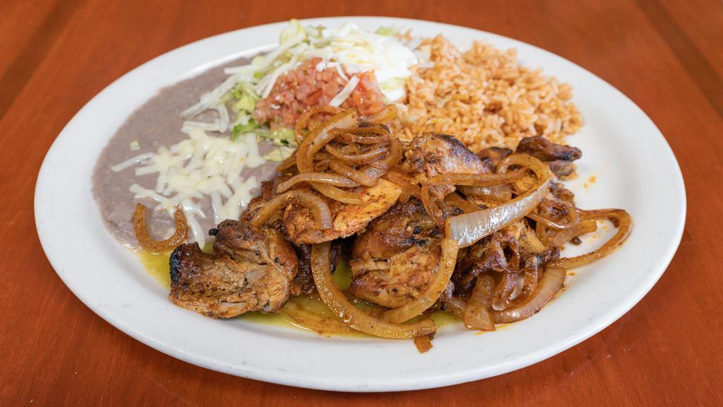 A. Pollo Adobado · Marinated chicken with tomatillo sauce served with rice and beans.