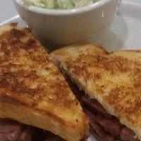 THE REUBEN · FRESH CORNED BEEF TOPPED WITH SAUER KRAUT AND SWISS CHEESE SERVED ON GRILLED RYE.