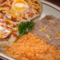 Huevos Rancheros · Two over-easy eggs in a crispy tortilla topped with cheese and ranchero sauce, served with r...