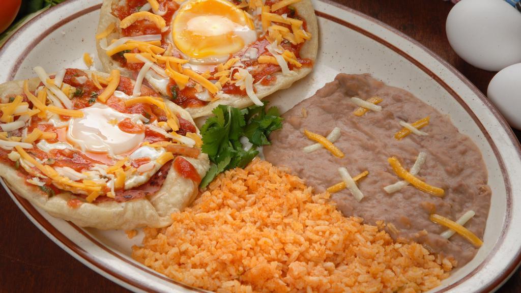 Huevos Rancheros · Two over-easy eggs in a crispy tortilla topped with cheese and ranchero sauce, served with rice and beans.
