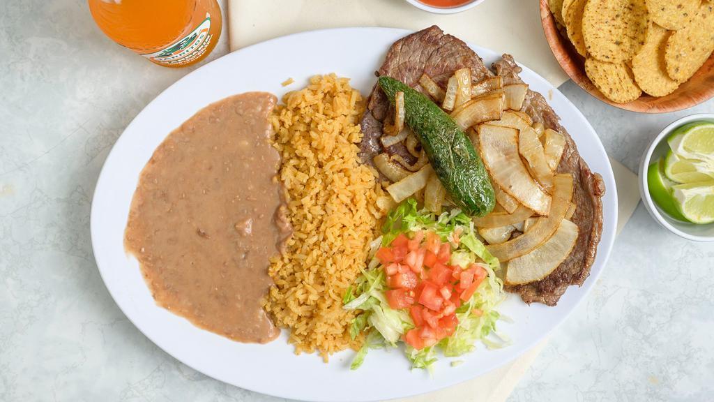 Carne Asada · Grilled steak with grilled onions on top. Served with beans, rice and tortillas