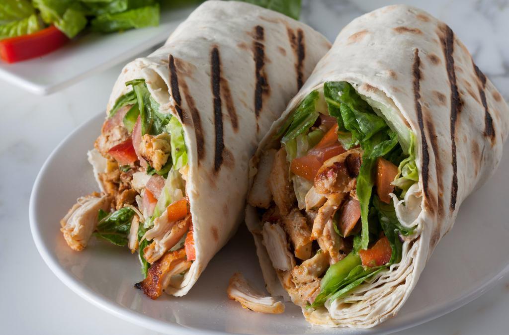 Chicken Shawarma · Seasoned sliced shawarma chicken with tahini, lettuce, and tomatoes topped with our house garlic sauce wrapped in a lavash.