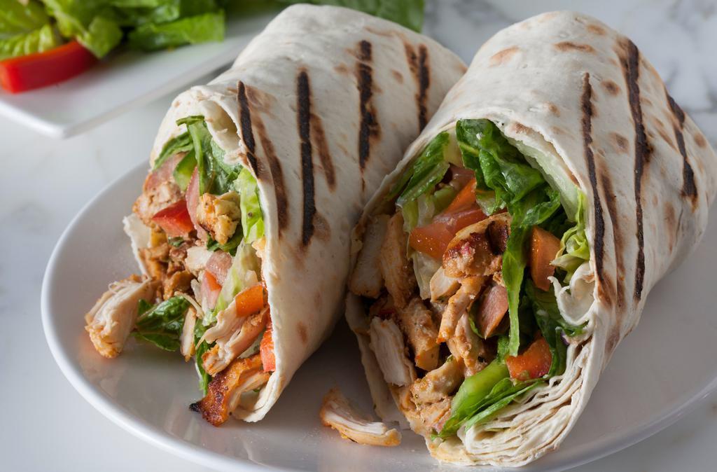 Chicken Shawarma Deluxe · Seasoned sliced shawarma chicken with tahini, lettuce, and tomatoes topped with our house garlic sauce, and added hummus falafel wrapped in a grilled lavash.